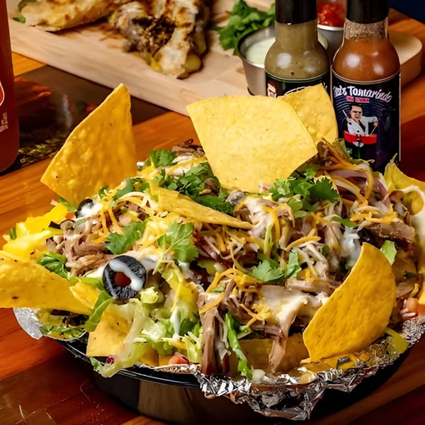 Hermanos Cantina Grill's loaded nachos with meat, cheese, lettuce, olives, and cilantro, with hot sauces.